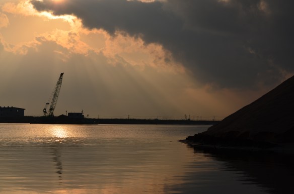 午後4時前なのに夕方のよう。正面は、覆砂作業中のクレーン付き台船。右は、浅場造成用の砂の山